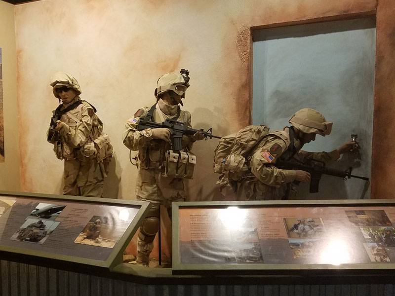 US Army display of a group of three Soldiers preparing to infiltrate a building.